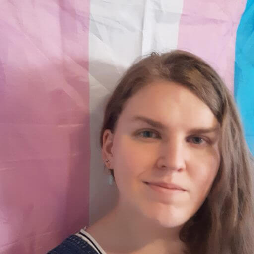 Jade Flohr standing in front of the trans flag