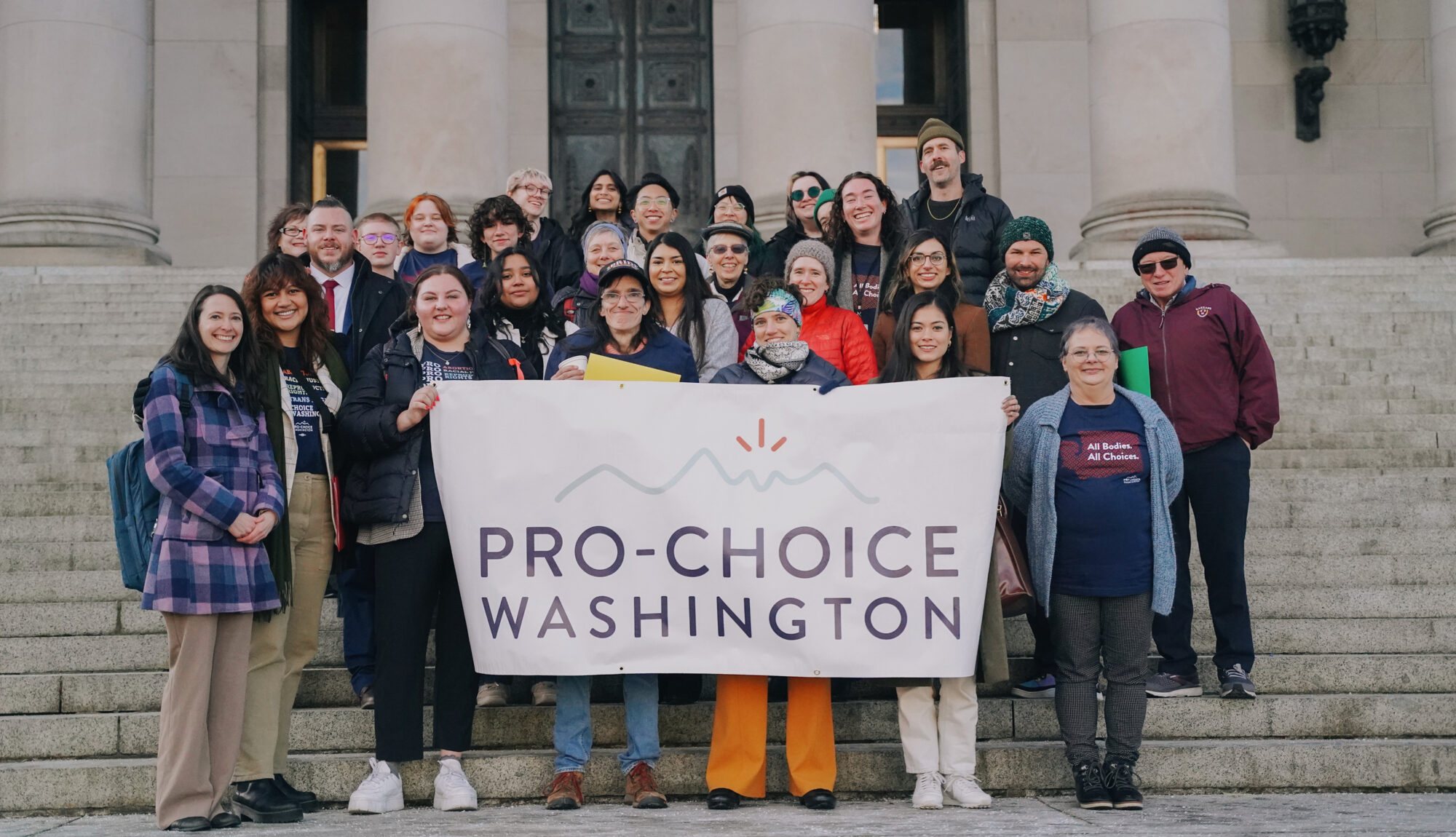 Pro Choice Washington activists on steps of capitol hold a white sign that reads Pro Choice Washington