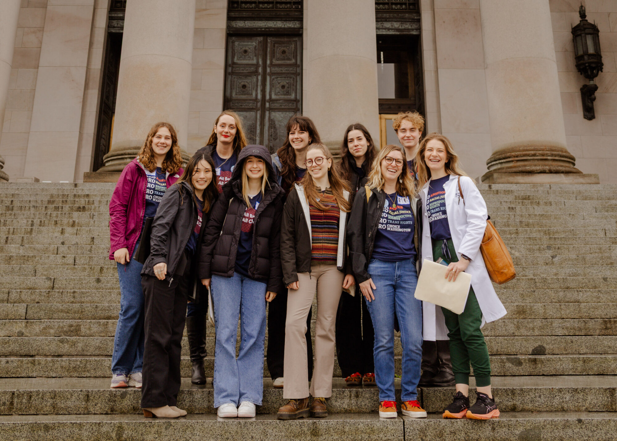 A group of student activists in plain clothes stand on the capitol steps