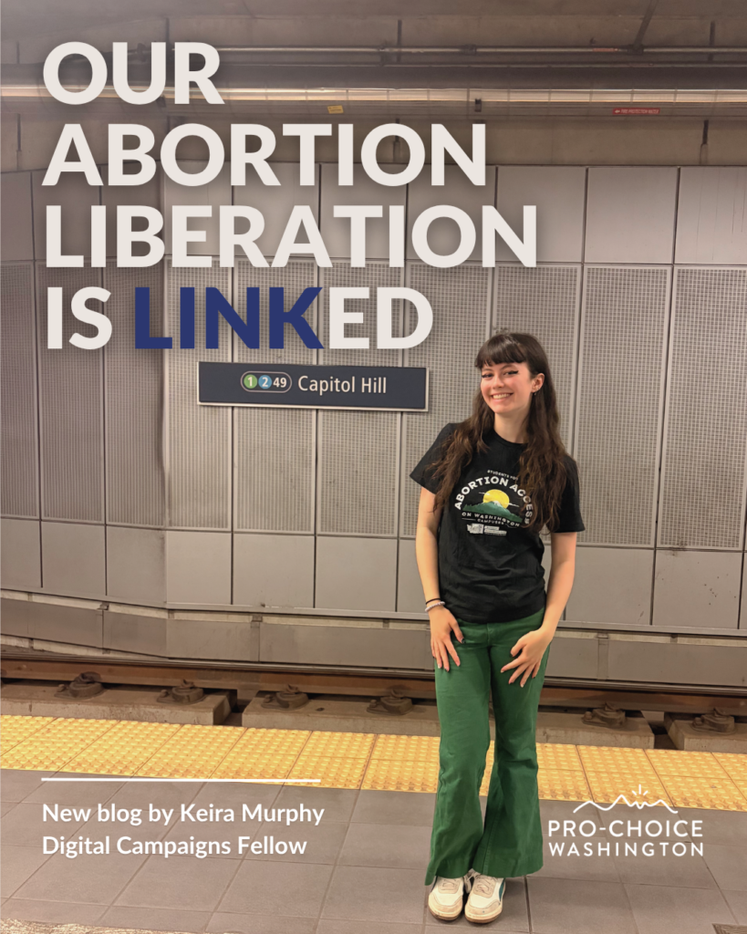 A smiling woman with brown hair poses in front of the Link light rail tracks.