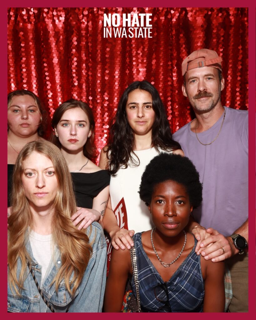 Pro-Choice Washington staff and board members posing in front of a red No Hate in Washington State backdrop.
